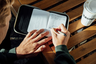 A man writing in his notebook with a pen.