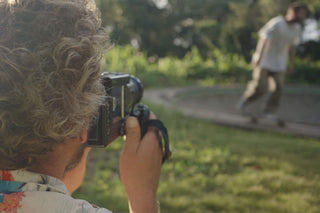 Arto Saari filming a skateboarder drop into a pool.