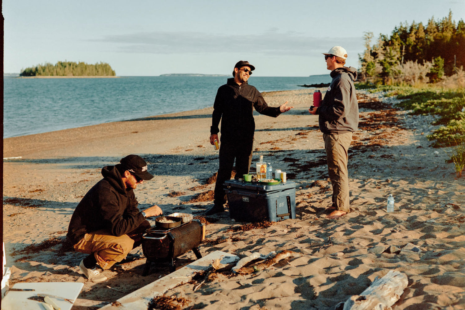 Three guys hanging out and cooking on a beach in Cow Bay, Nova Scotia.