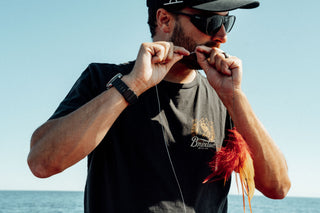 A man biting through fishing line.