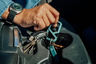 A person picking up his EDC carabiner with keys and a small pocket knife attached.